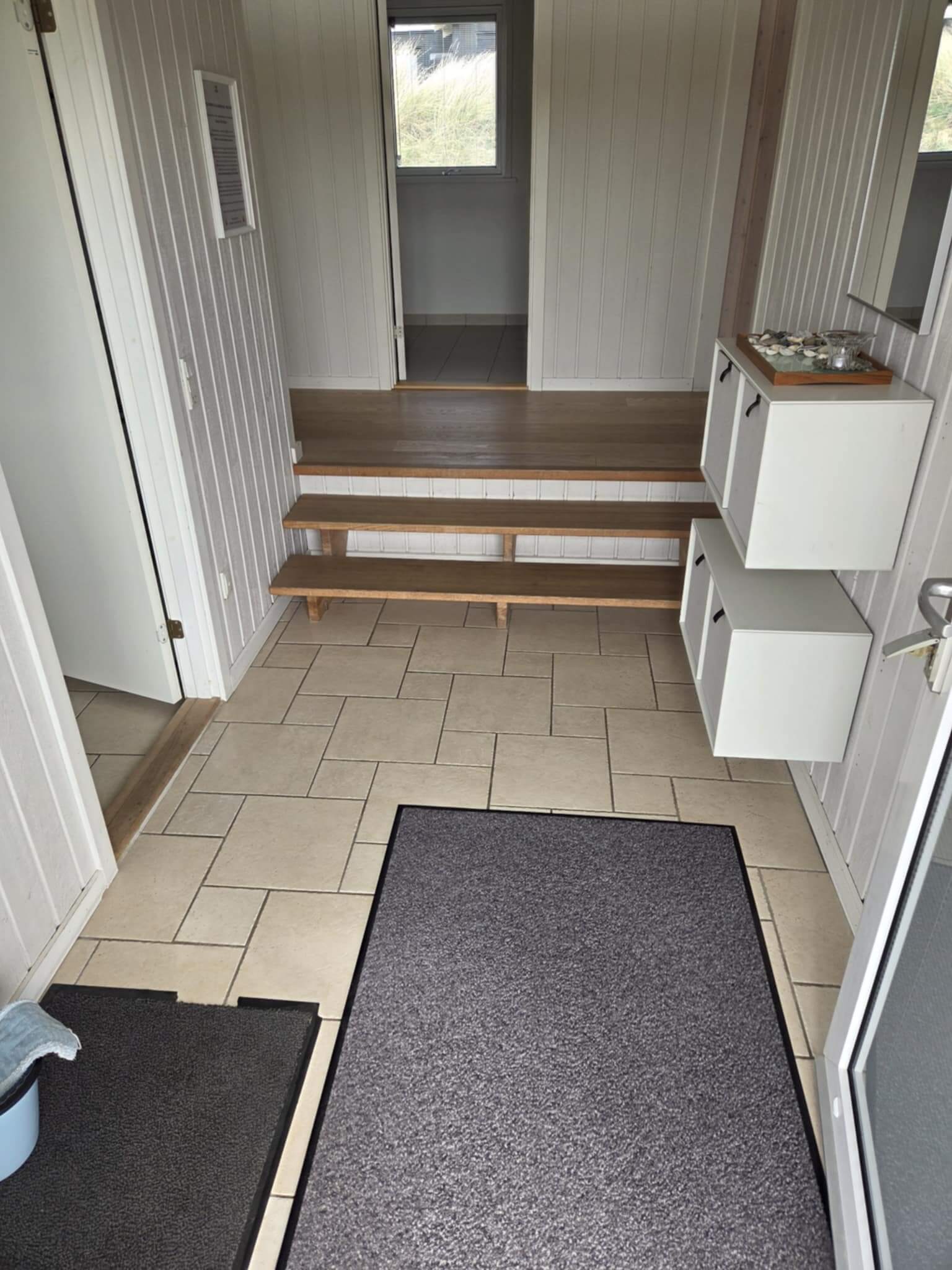 Rengjort entré med pæne fliser og velholdte møbler.